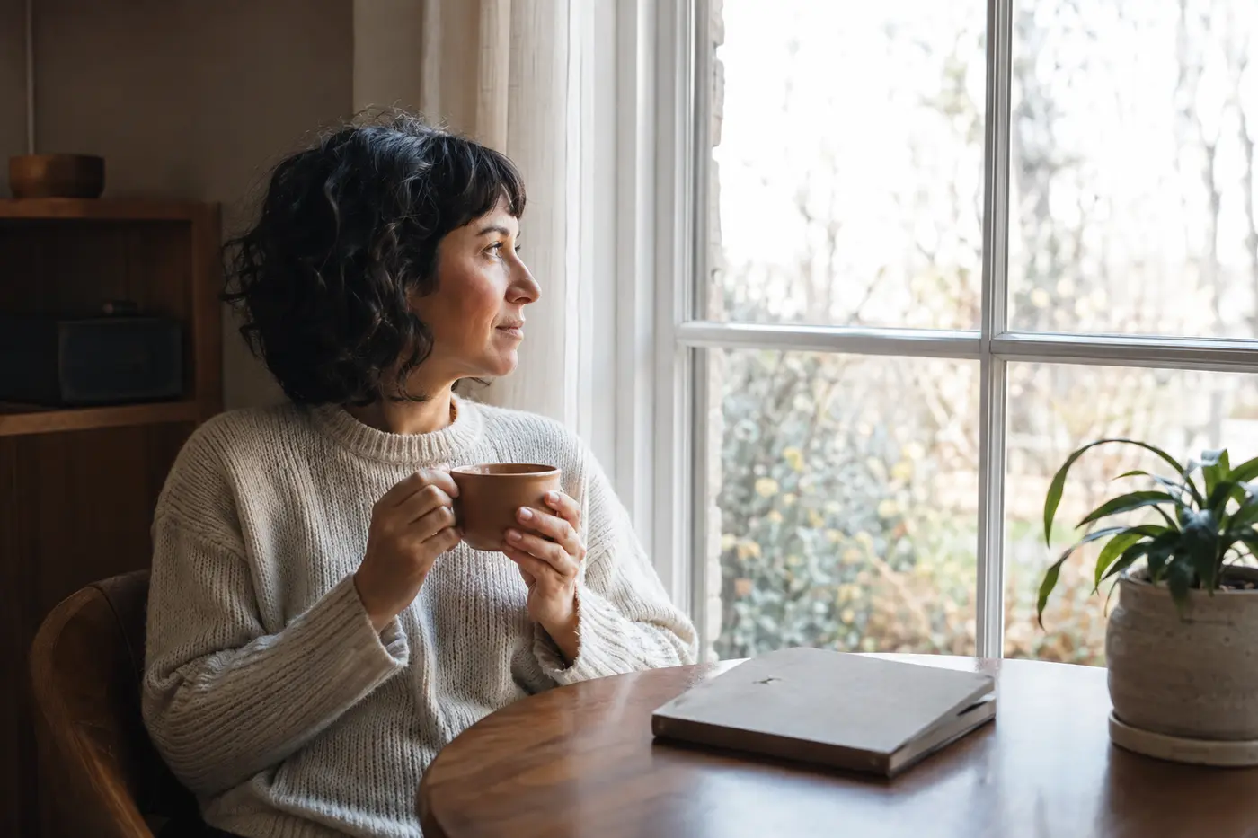A person quietly noticing an ordinary morning moment beside a window